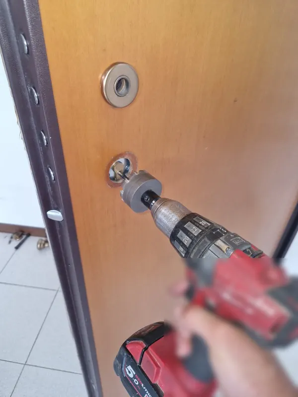 Fabbro al lavoro sul cilindro di una porta blindata a Medicina